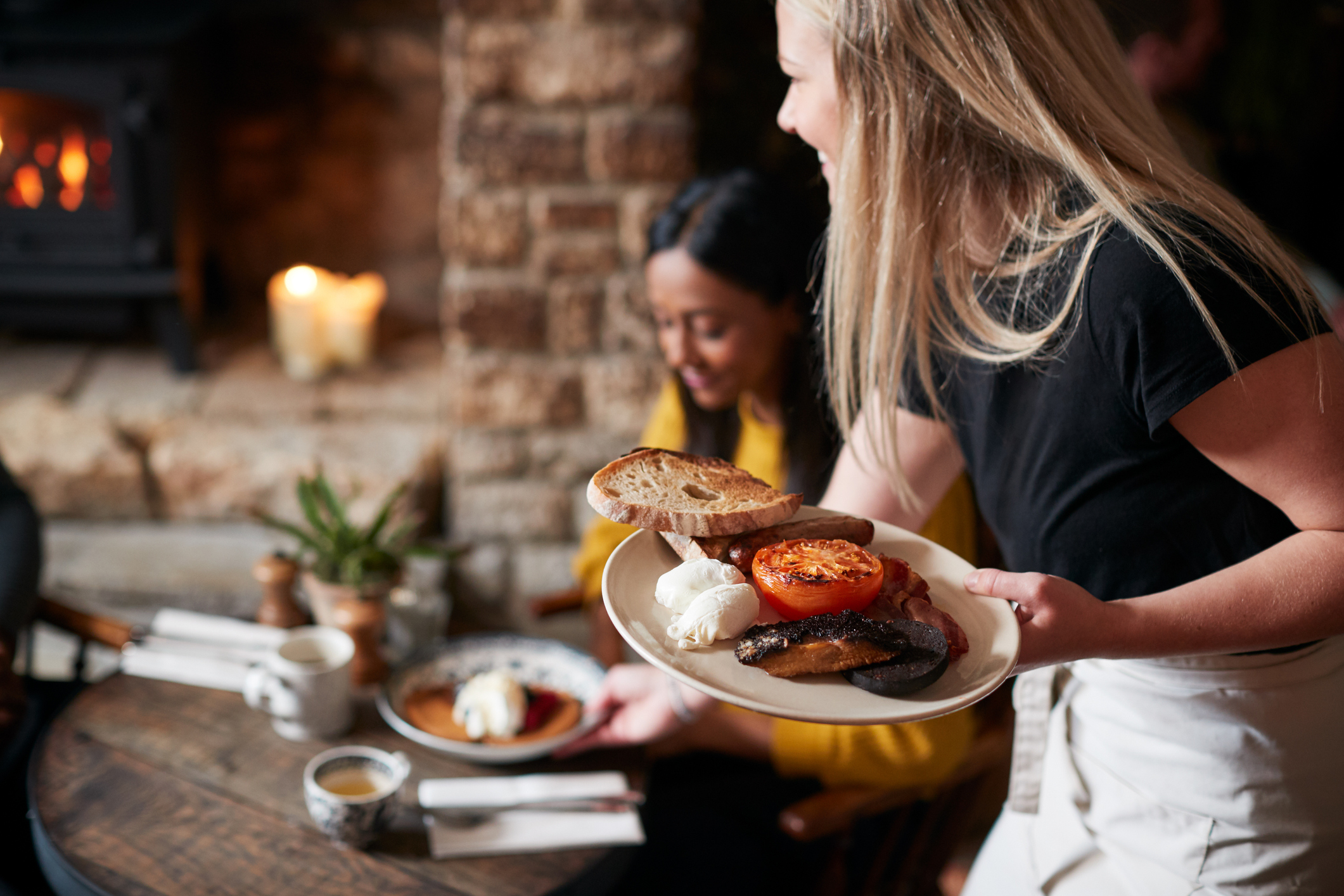 Close Up Of Waitress Working In Traditional English Pub Serving Breakfast To Guests